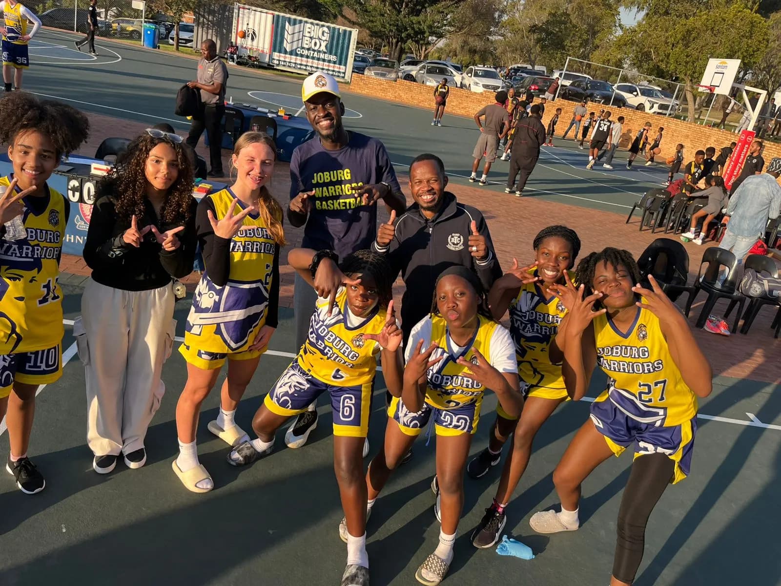 Joburg Warriors girls' squad and coaches celebrating together courtside at golden hour