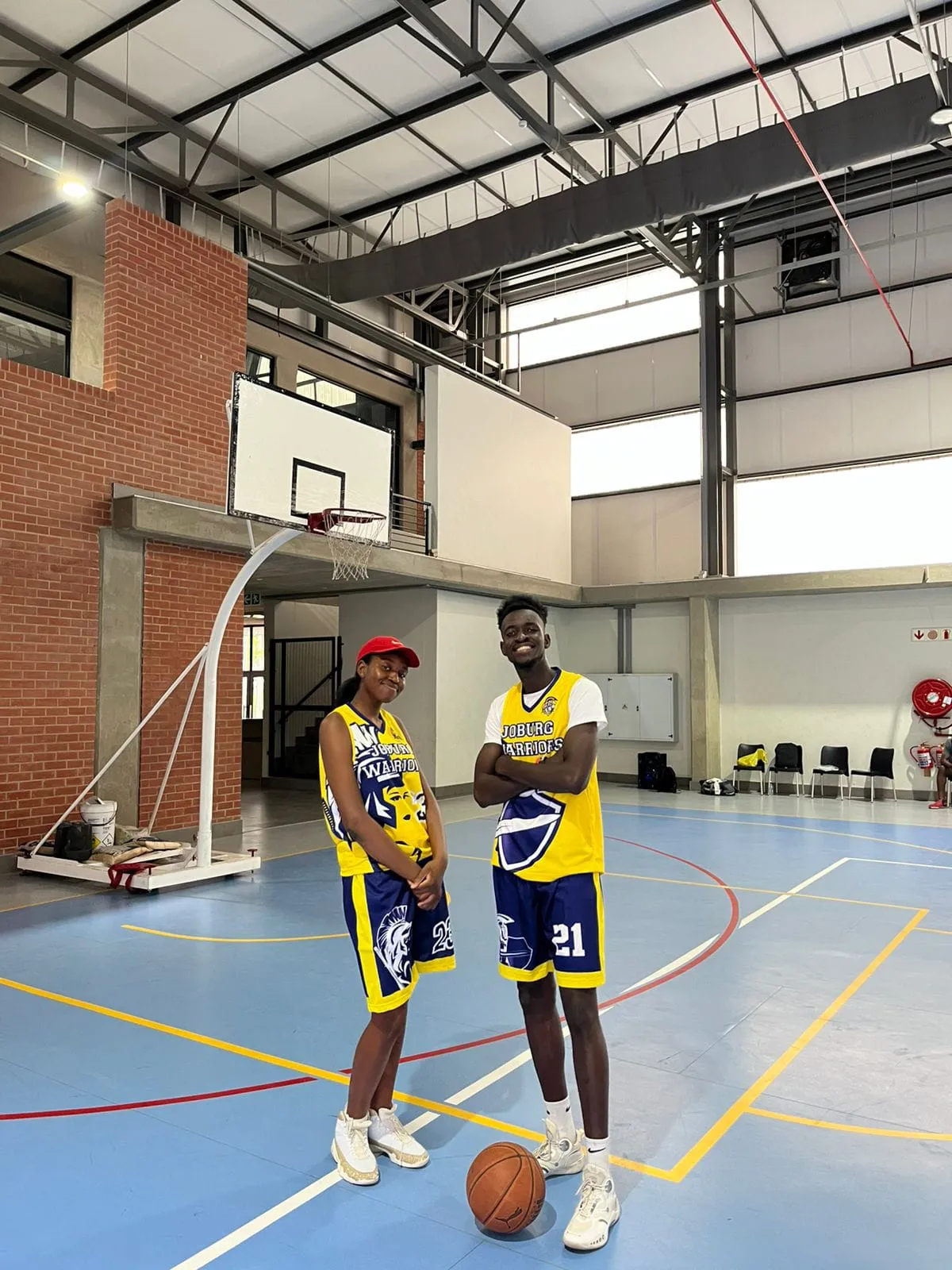 Two Joburg Warriors players in gold and indigo kit on an indoor court